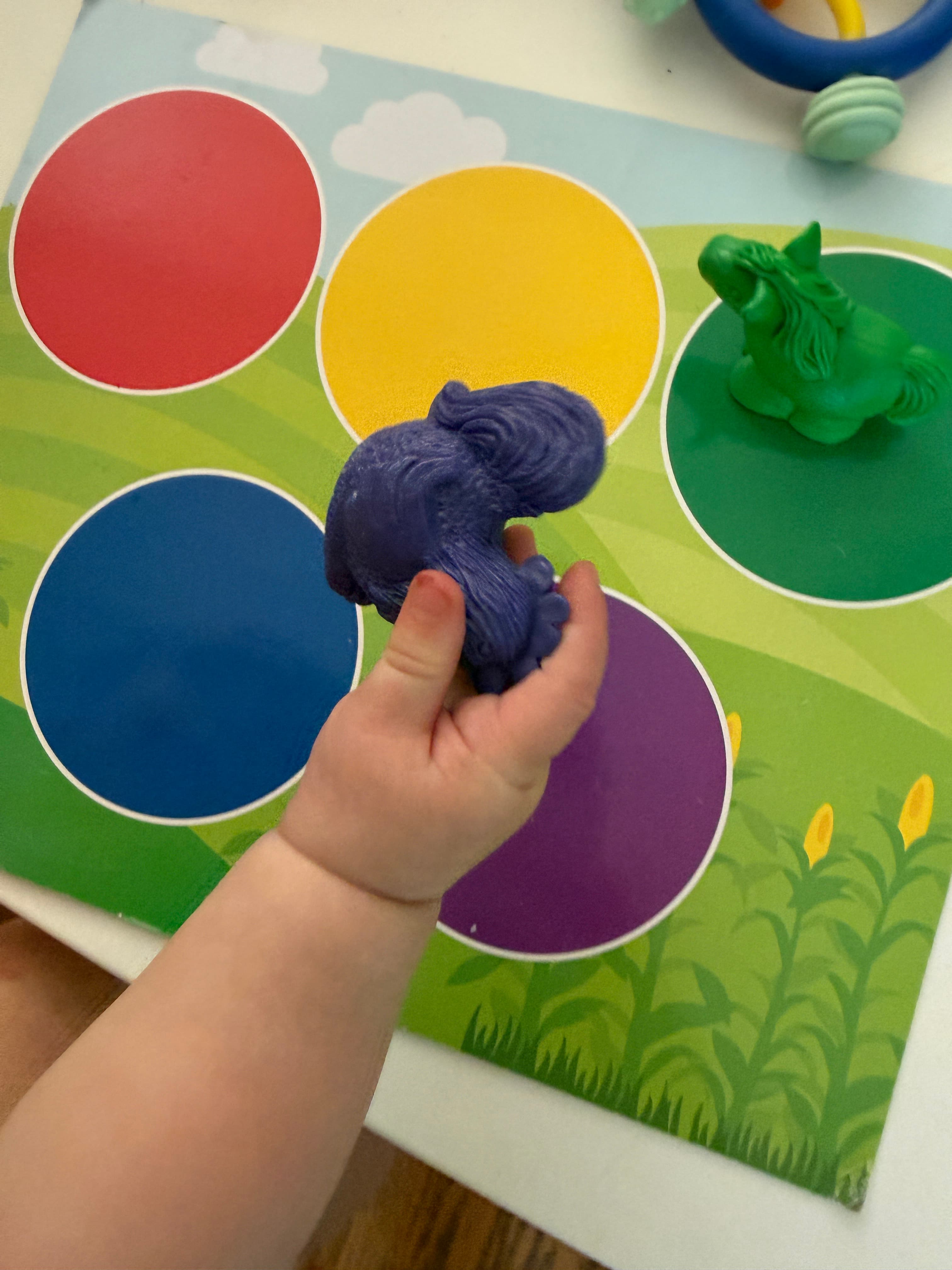 A young child's hand placing a purple toy on a color-sorting board during a mindful learning activity