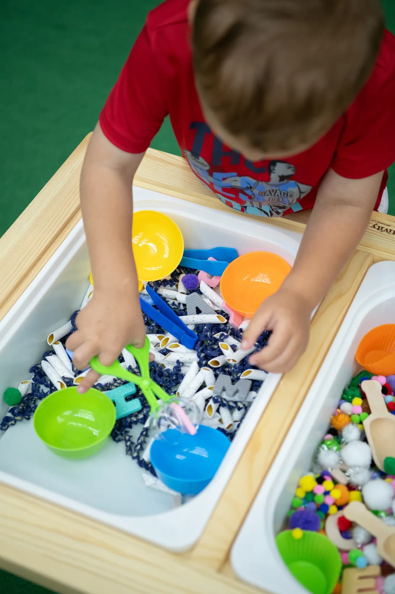 A child scooping and exploring a sensory bin at a CHAMP Academy class