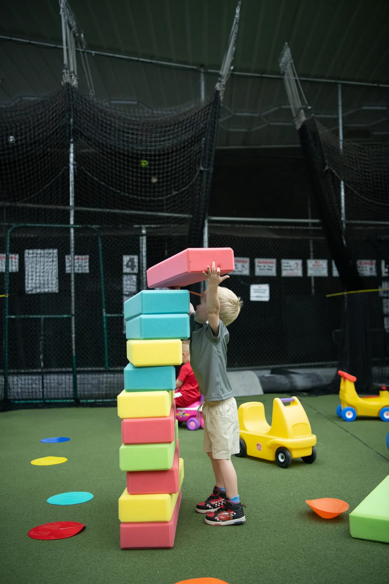 A child stacking tall foam blocks into a tower at The Hitter's Edge