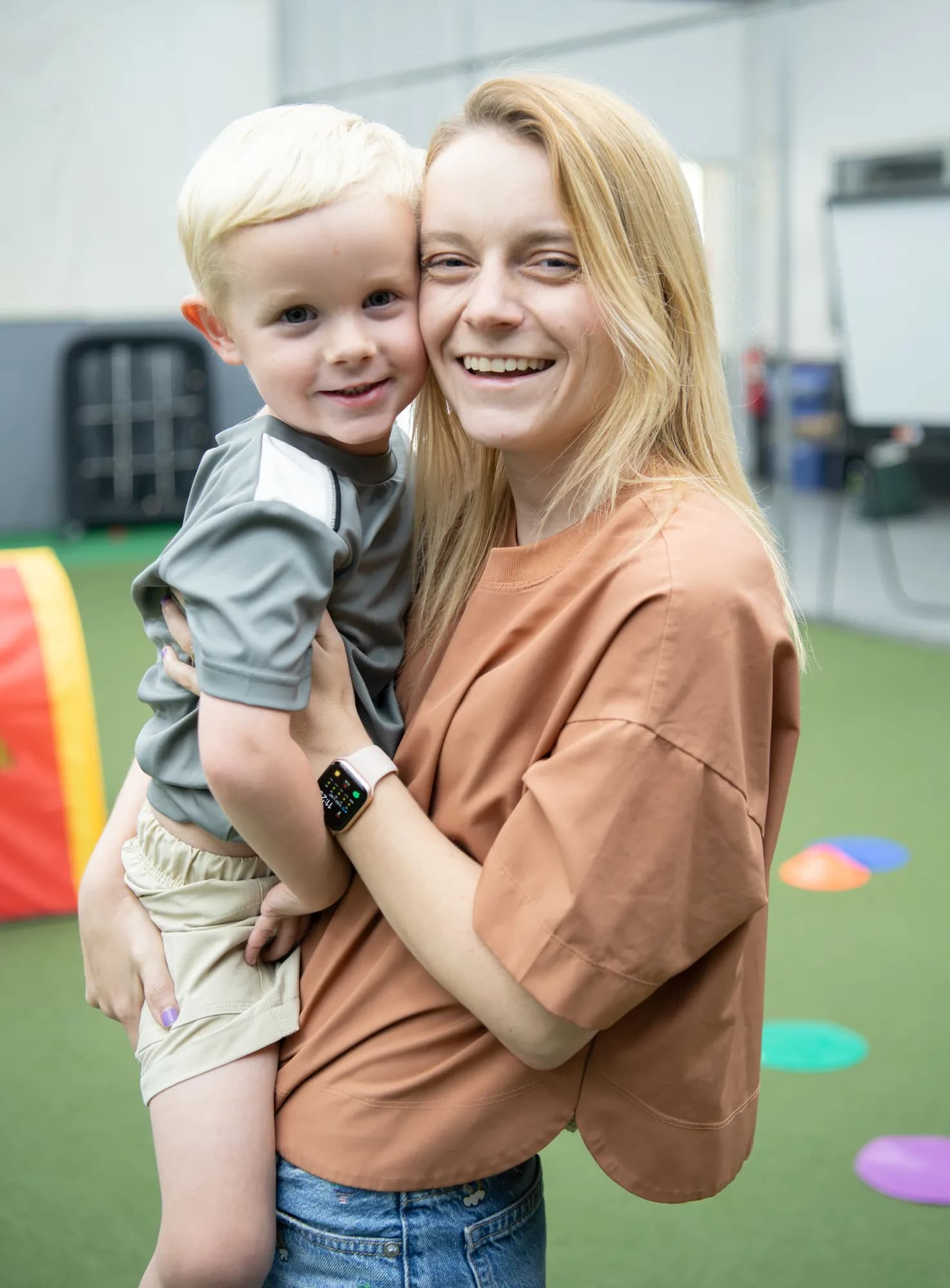 A young boy smiling in the arms of a CHAMP Academy educator