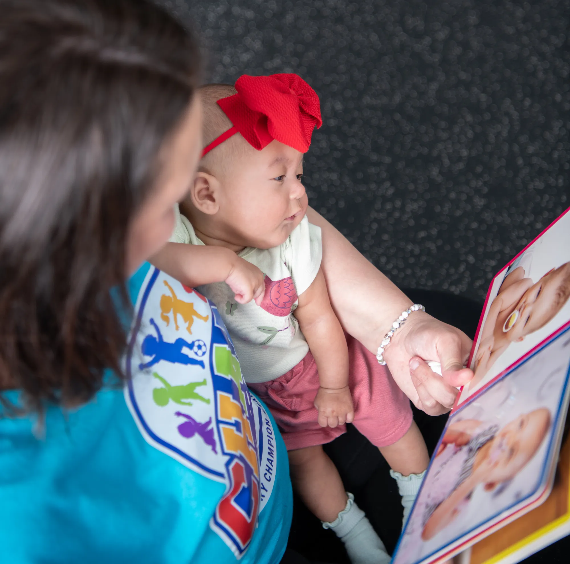 A CHAMP Academy educator reading a board book to a baby