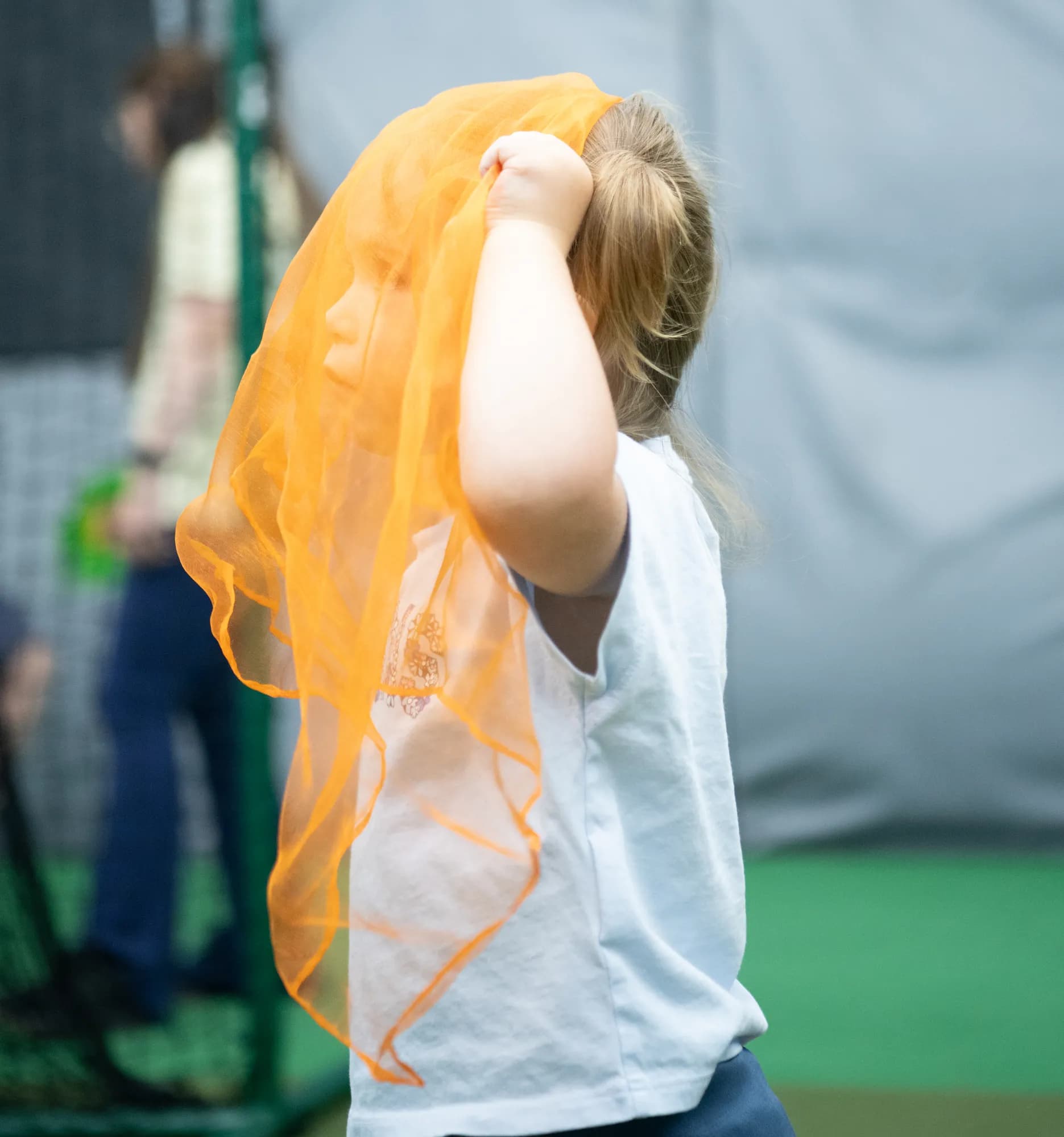 A child playing with a flowing orange scarf during a CHAMP Academy movement class